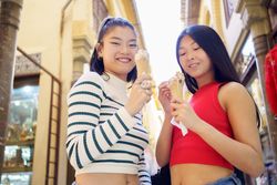 Two young Chinese women eating an ice cream cone in the typical streets of Granada