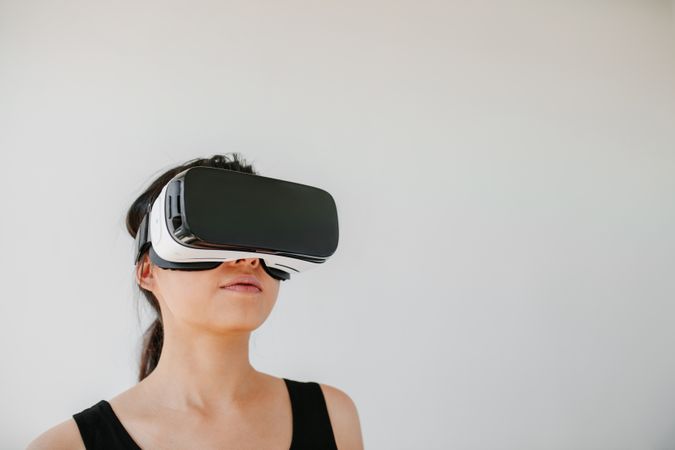 Shot of young woman using the virtual reality headset against grey background