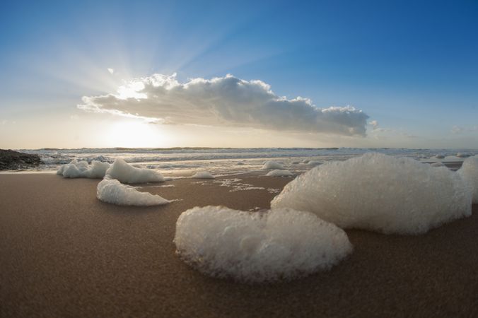Coast with foam of sea and blue sky with cloud