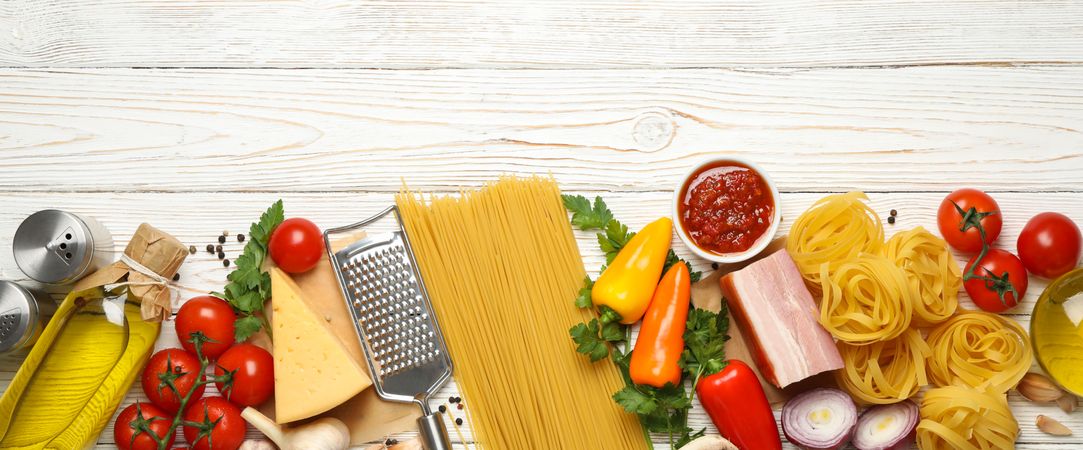 Composition with pasta and ingredients for cooking on wooden background, top view