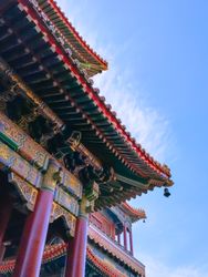 Intricately designed Chinese architecture with vivid red and gold tones, against a clear sky