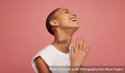 Female with shaved head smiling on pink background bxYNB0