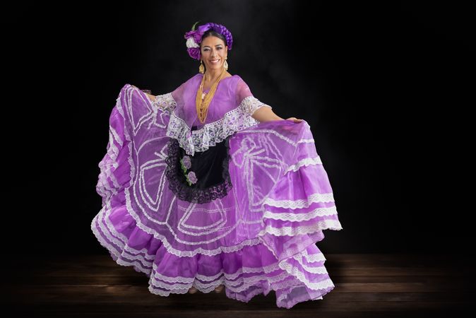 Woman in purple Chiapas dress standing against dark background