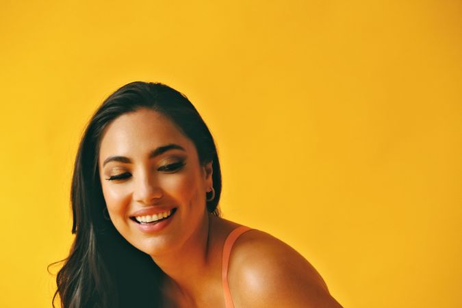 Headshot of Hispanic woman bent over with laughter in yellow room