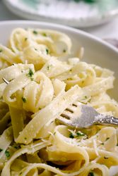 Cooked tagliatelle pasta with pesto sauce on fork