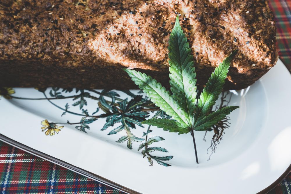 Close up of a baked grainy loaf with a marijuana leaf