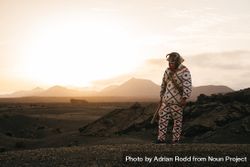 Person in brightly patterned clothes and devil mask standing on volcanic hills in Lanzarote at dusk 0gJaeb