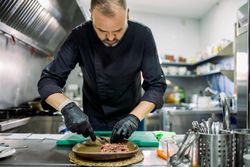 Male serving meat on plate in restaurant kitchen