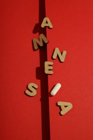 Vertical composition of a dark line with scattered letters saying “Amnesia”