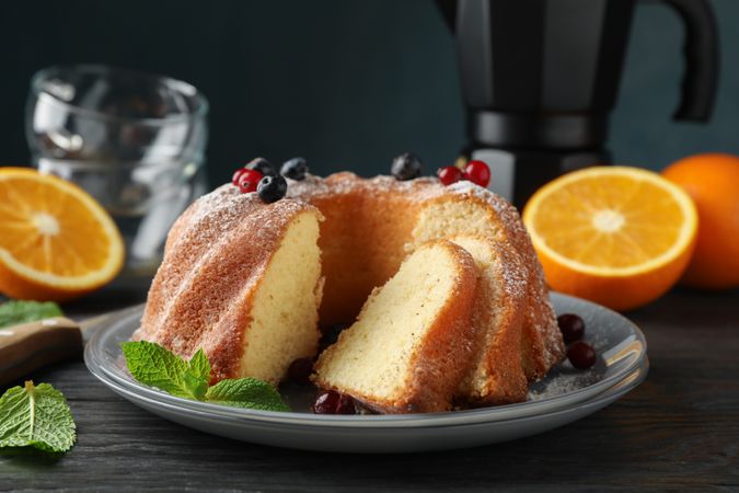 Cake with powdered sugar, berries and mint on wooden background, close up