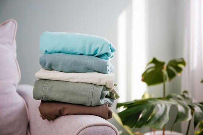 Pile of colorful warm clothes on the grey sofa.