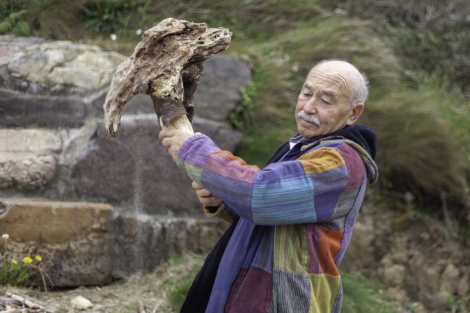 Grey haired man breaking stone formation