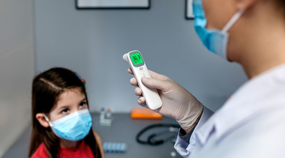 Female doctor looking at infrared thermometer after taking tempe