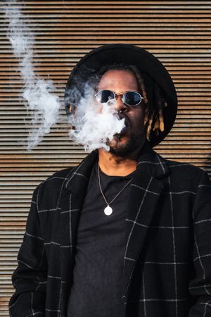 Trendy Black man in hat smoking