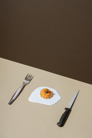 Egg with pumpkins as yoke with knife and fork
