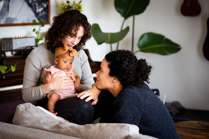 Happy new family with baby interacting in living room at home