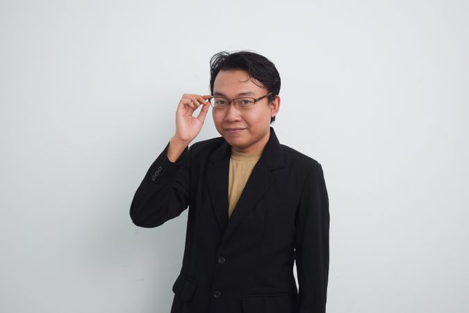 Happy Asian businessman adjusting glasses