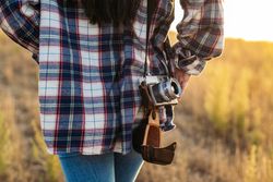 Unrecognizable woman taking photos with analog camera in the countryside