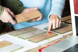 Anonymous woman choosing sample with carpenter in workshop