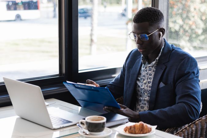 Focused Black male entrepreneur taking notes during work in cafe