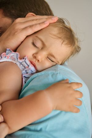 Father holding sleeping daughter in arms