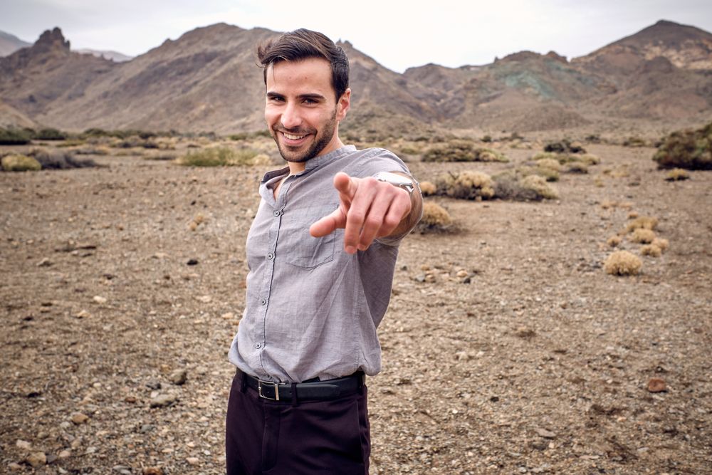 Man pointing with forefinger and looking at camera in highlands