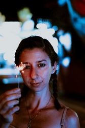 Woman holding sparkler on fairground in evening