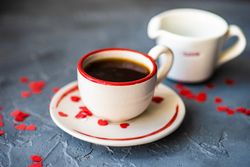 St. Valentine day card concept of coffee with red heart confetti served and cream