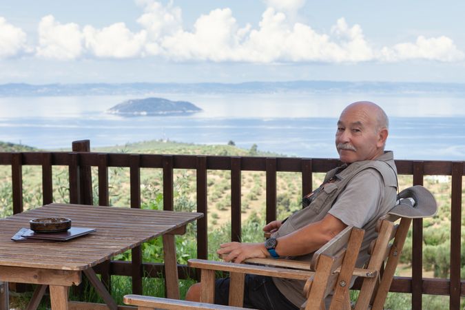 Relaxing man sitting on wooden terrace with seascape