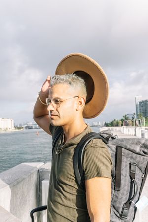 Young man with glasses taking out his hat for the heat in a summer day.