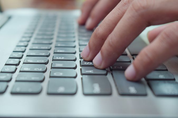 Close up side view young man typing on laptop