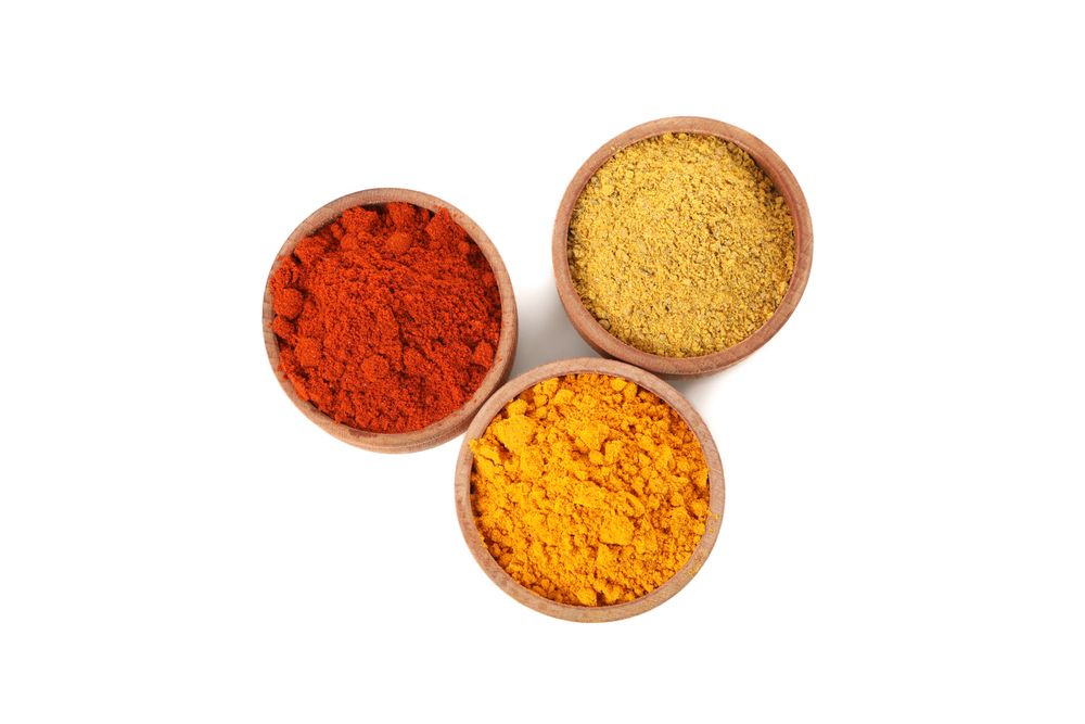 Top view of three wooden bowl full of different spices