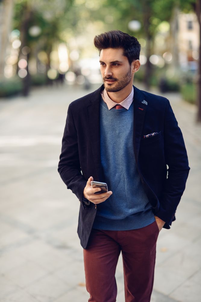 Sharply dressed man in the street wearing suit with smart phone in his hand, vertical