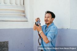 Man with beard laughing while taking photos holding digital camera outside 4Azdmb