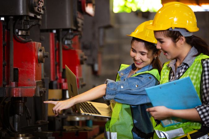 Two female engineers or technician worker wearing safety hard helmet in factory