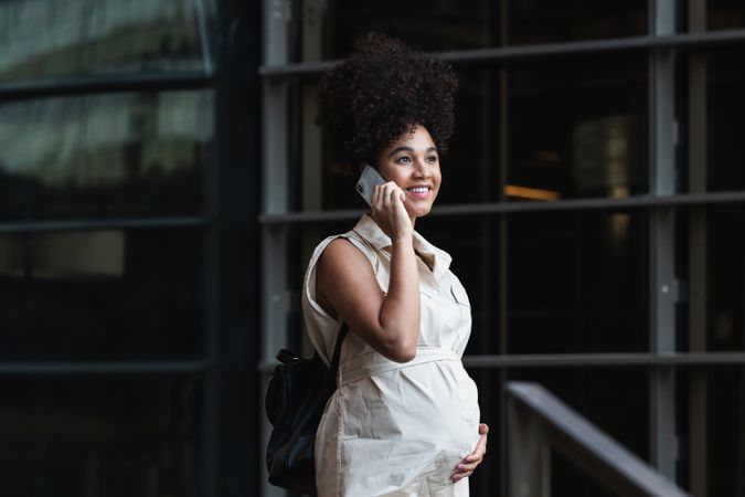 Smiling Black pregnant woman talking on smartphone