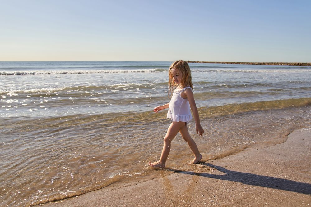 a little girl at the seashore entering the water