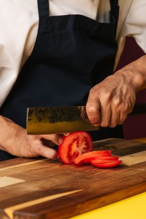 Cropped image of chef chopping tomato