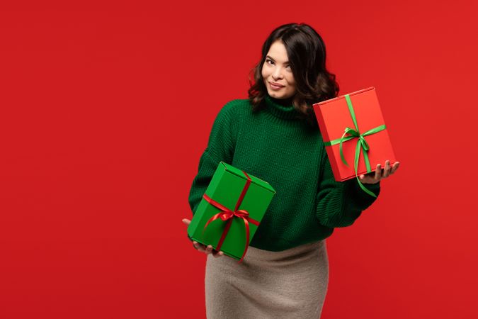 Playful woman holding two colorful gift boxes with bows