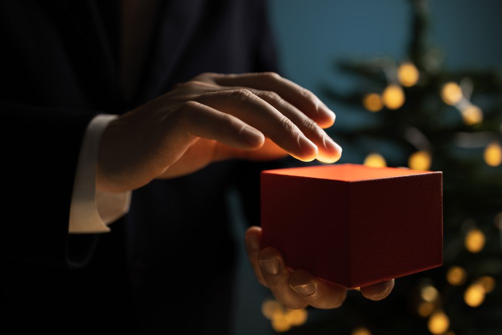 Businessman holding Christmas gift near tree