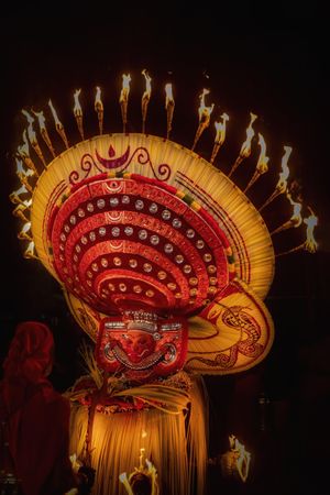 Man performing Theyyam ritual holding fire at night