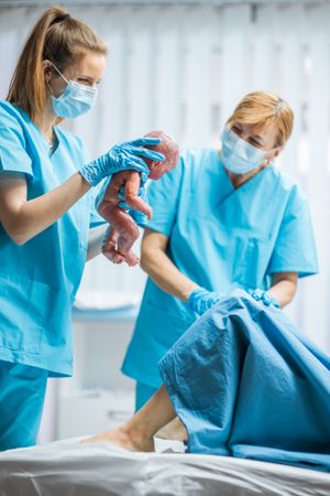 In the Hospital Woman in Labor Pushes and Gives Birth, Baby Comes out, Obstetricians Holds Infant Baby