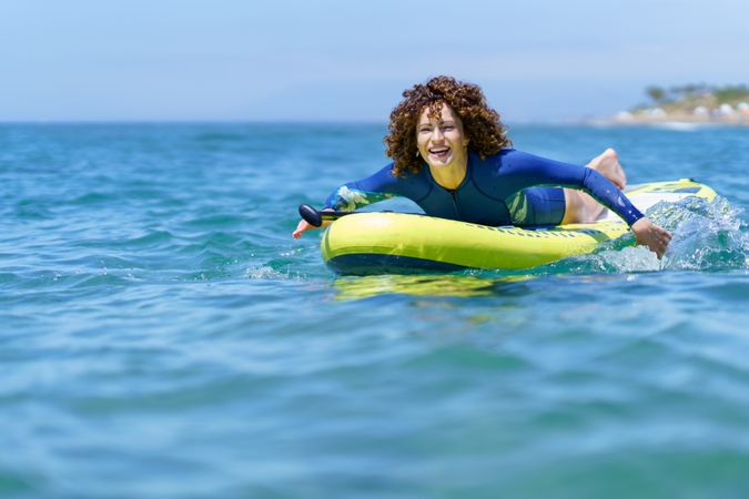 Cheerful woman pulling SUP board in seawater