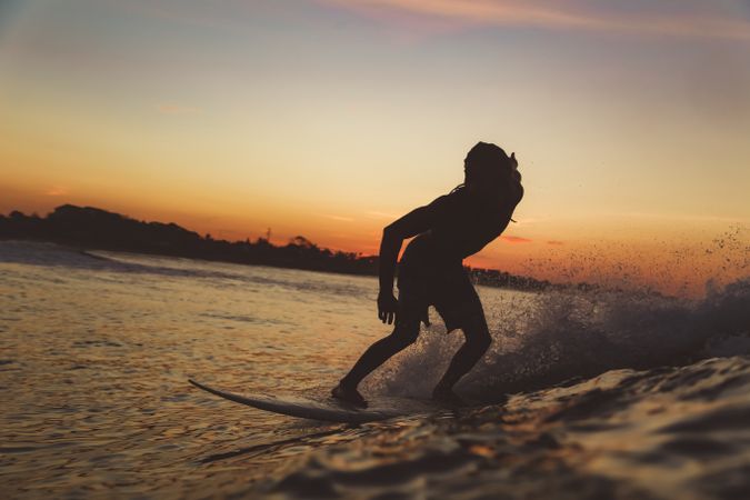 Man on surf board on waving water at sunset