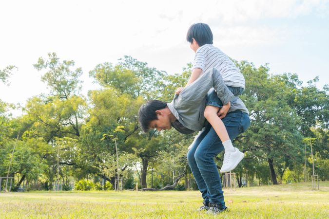 Boy raising arms up in the air on his father’s back