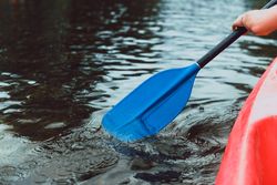 Faceless sportsman kayaking on lake