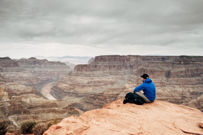 Male relaxing on cliff and admiring picturesque view