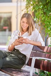 Smiling woman with smartphone on bench