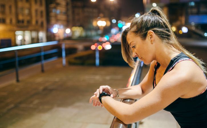Portrait of female runner checking heart rate monitor on smart watch app after training