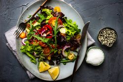 Top view of organic vegetable salad with side of salt and sesame seeds